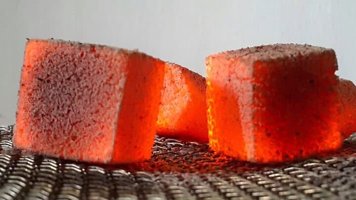 Glowing charcoal briquettes on a mesh grill rack